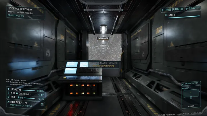 A first-person view looks through a glass airlock toward a lit workshop corridor.